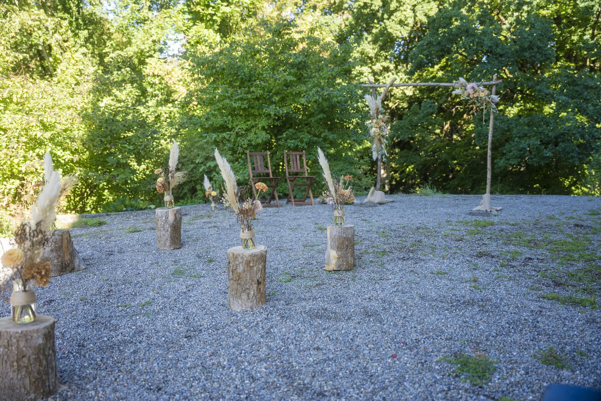 Freie Trauung im Grünen: Holzstämme mit Trockenblumen säumen den Platz