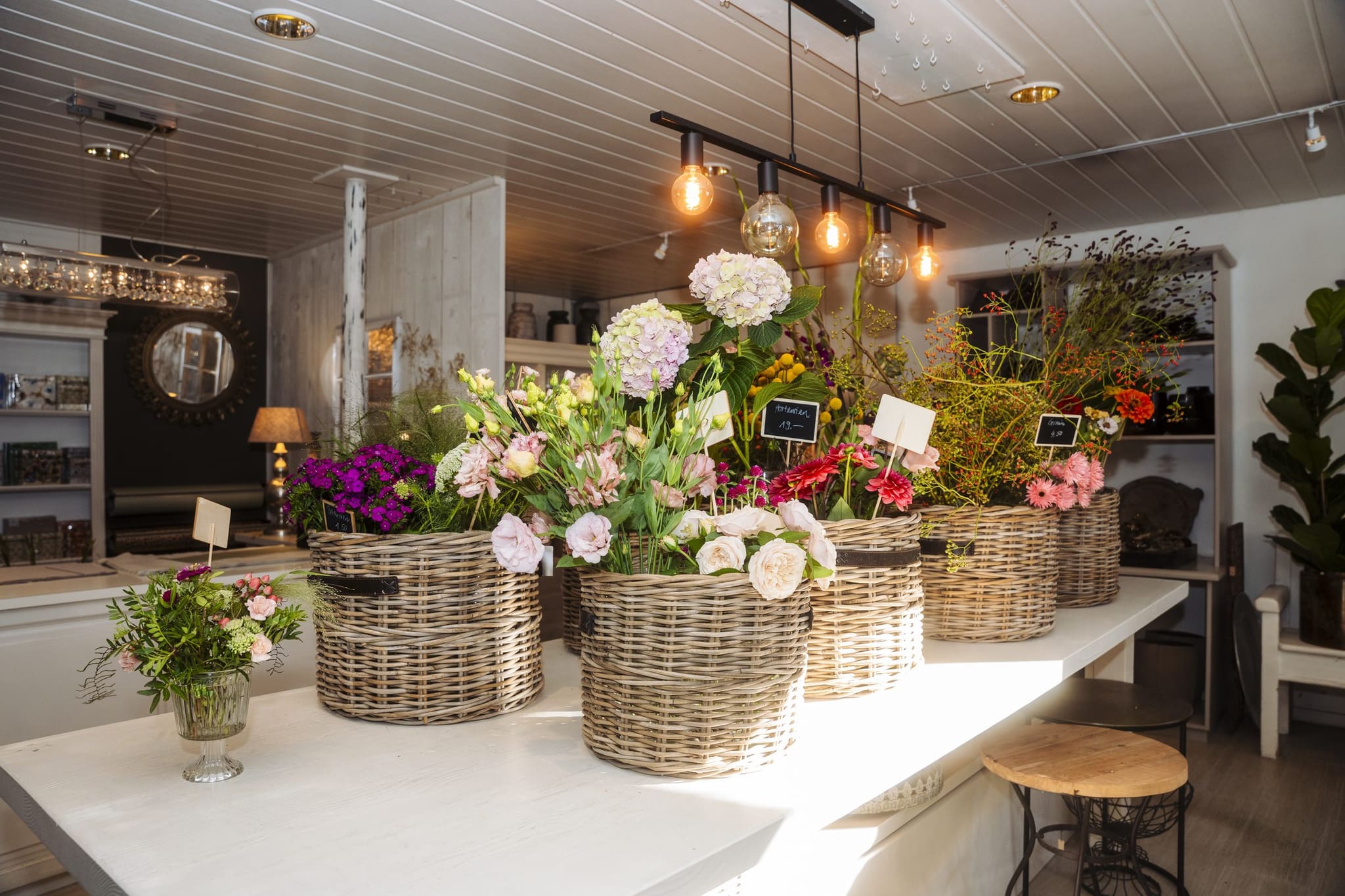 Blumenkörbe mit Hortensien und Rosen auf der weissen Theke