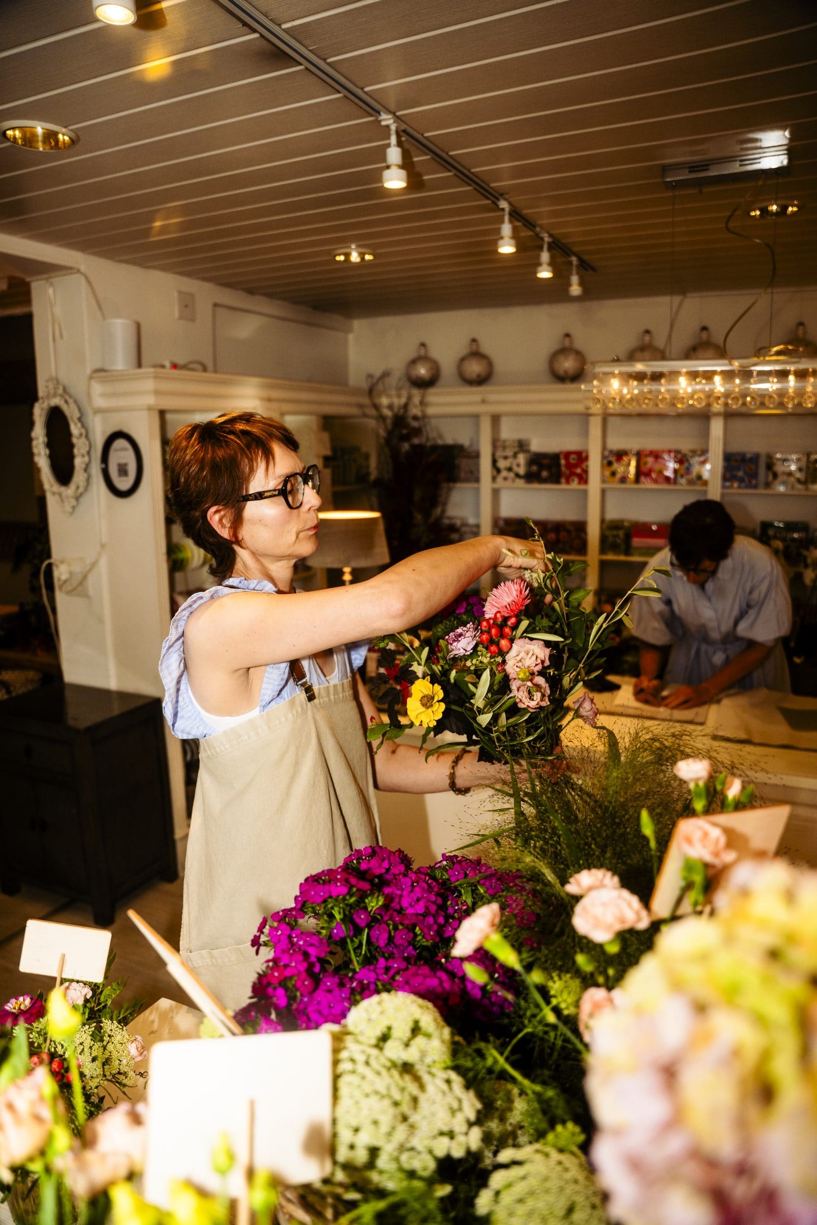 Floristin arrangiert Blumen am Arbeitstisch in unserem Geschäft