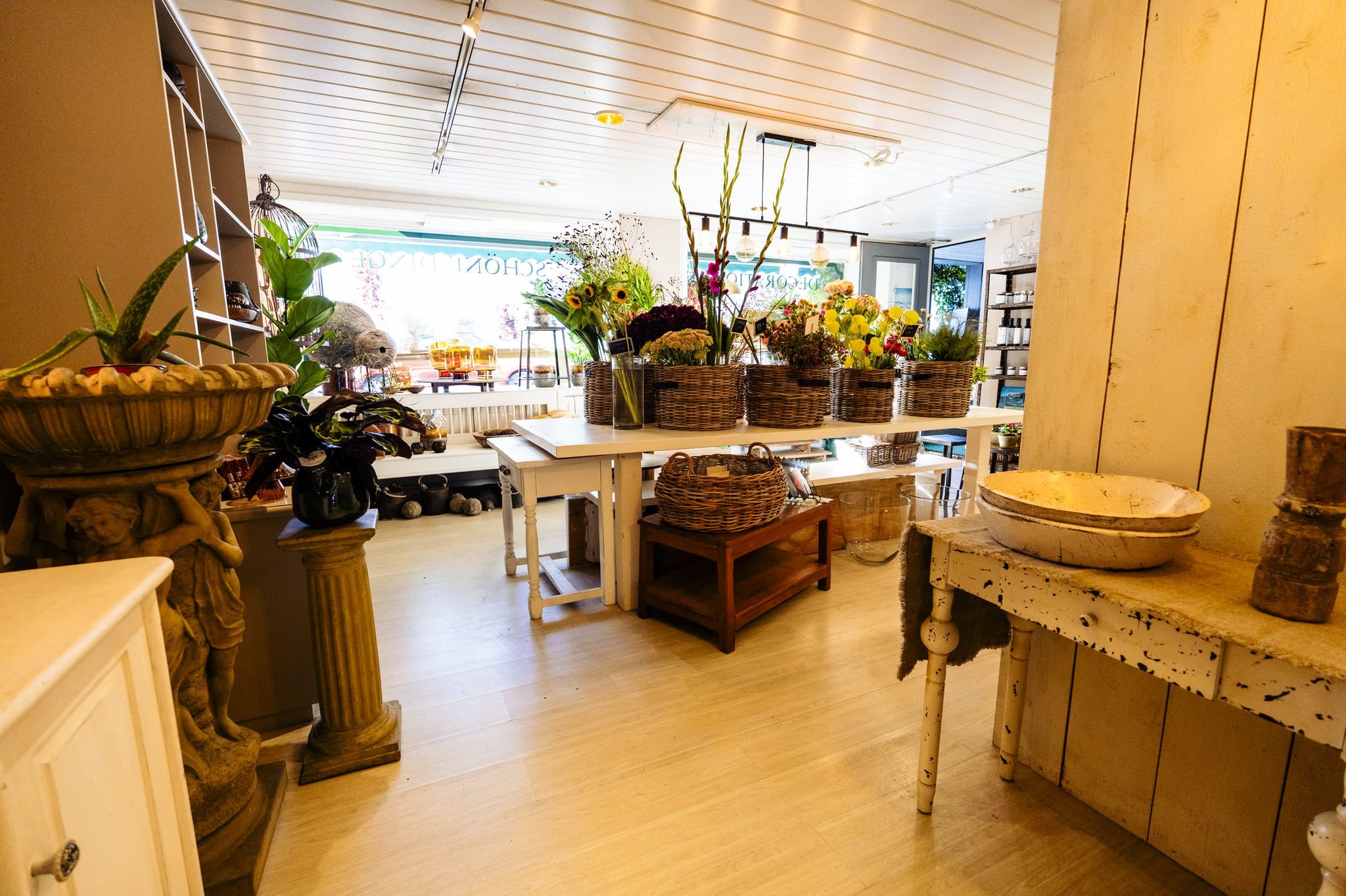 Holztische, Pflanzen und Blumenkörbe in unserem Geschäft
