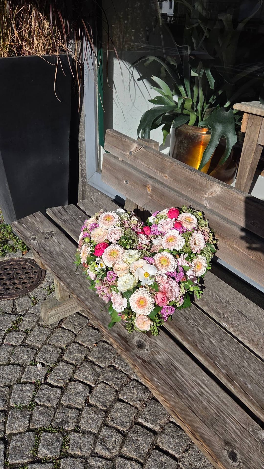 Blumenherz aus rosa und weissen Rosen auf einer Holzbank