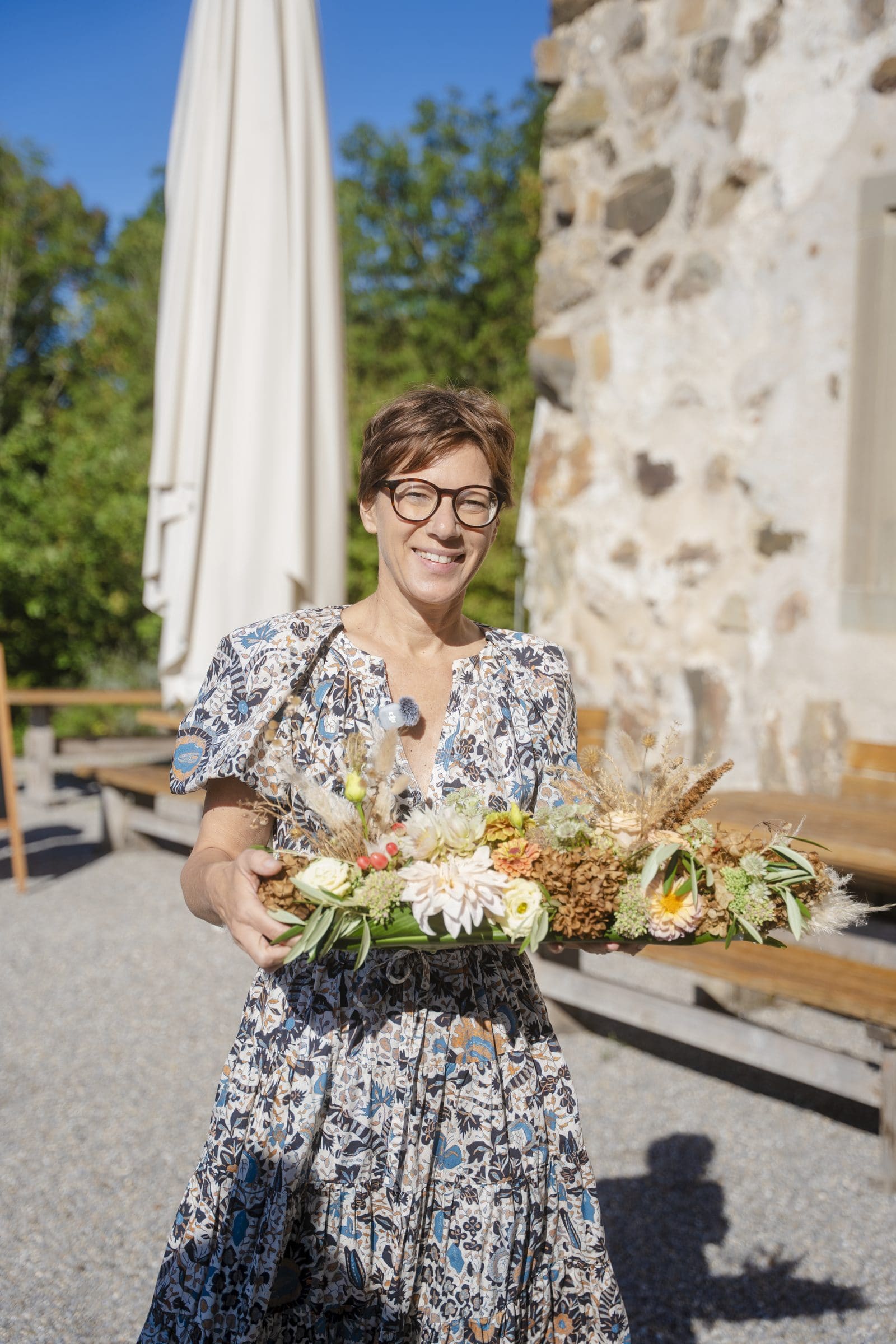Floristin mit einem langen Gesteck aus Dahlien und Gräsern